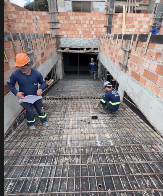 Equipe trabalhando na armação de uma laje entre paredes de alvenaria